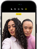 iPhone 18 Pro, สีดำ, ภายนอกด้านหน้า, แสดงให้เห็นสองคนกำลังโพสท่าให้กล้องเพื่อสาธิตกล้องหน้า Center Stage