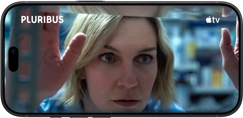 iPhone 18 Pro, โหมดแนวนอน, แสดงภาพระยะใกล้ของผู้หญิงที่กำลังมองผ่านหน้าต่าง ชื่อซีรีส์: Pluribus