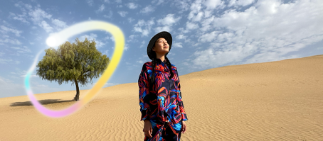 iPad Pro, จอภาพภายนอกด้านหน้าที่มีพื้นหลังสีน้ำเงินเข้มและสีเขียวไล่ระดับ พร้อมแอปหลายแอปที่เปิดอยู่, มือข้างหนึ่งถือ Apple Pencil Pro กำลังวาดวงกลมรอบภาพสเก็ตช์ที่แสดงคุณสมบัติไม้เสกภาพของ Apple Intelligence