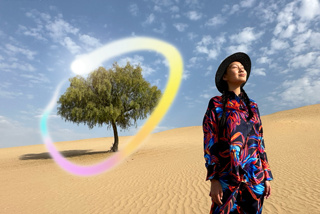 iPad Pro, จอภาพภายนอกด้านหน้าที่มีพื้นหลังสีน้ำเงินเข้มและสีเขียวไล่ระดับ พร้อมแอปหลายแอปที่เปิดอยู่, มือข้างหนึ่งถือ Apple Pencil Pro กำลังวาดวงกลมรอบภาพสเก็ตช์ที่แสดงคุณสมบัติไม้เสกภาพของ Apple Intelligence